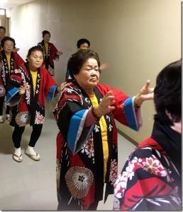 廊下で整列しながら踊りを復習している女性の写真